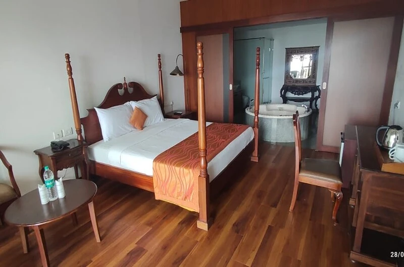 Traditional bedroom with an elegant wooden four-poster bed at Thayil Kadaloram Homestay Kovalam