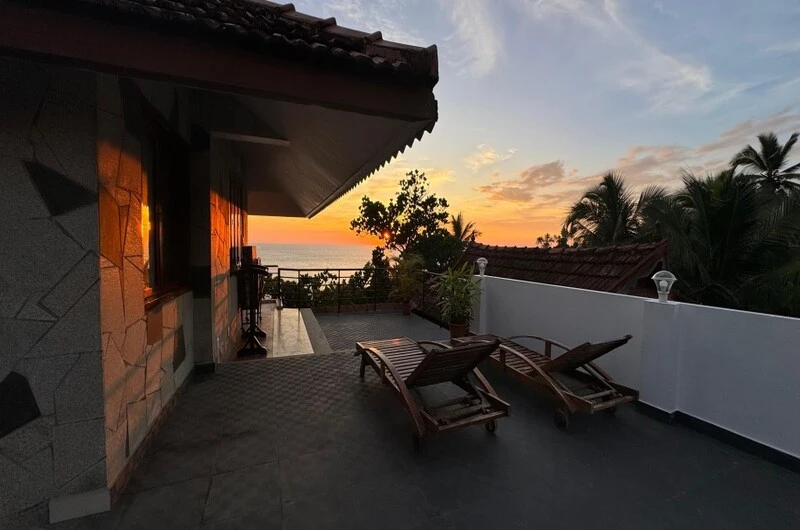 Scenic sunset view from the outdoor terrace balcony with lounge chairs at Thayil Kadaloram Homestay Kovalam