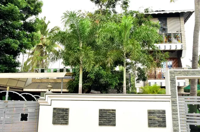 Exterior view of Mary Land Homestay building surrounded by lush green trees in Kovalam Kerala