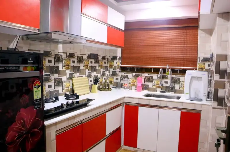 Modern modular kitchen setup with red and white cabinets at Mary Land Homestay