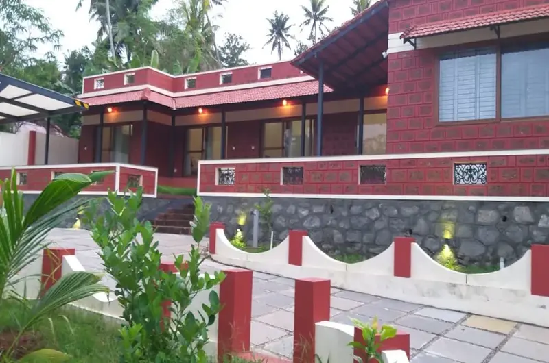 Exposed red brick exterior of The Ixora Boutique Homestay with lush tropical landscaping