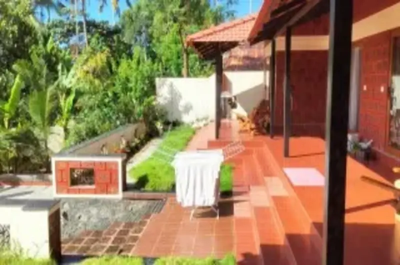 Scenic brick-paved garden pathway surrounded by lush tropical greenery at The Ixora Homestay Kovalam.