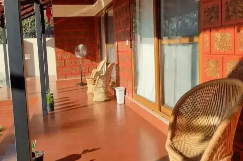 emi-open corridor or sit-out area featuring warm terracotta-colored walls and traditional wooden furniture.