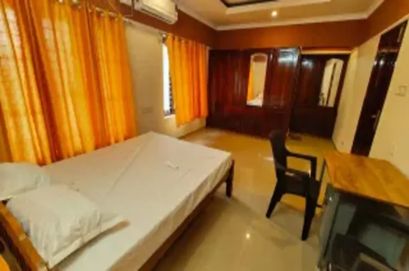 Well-lit premium bedroom interior with a single bed and study desk at Therickal Homes Kovalam.