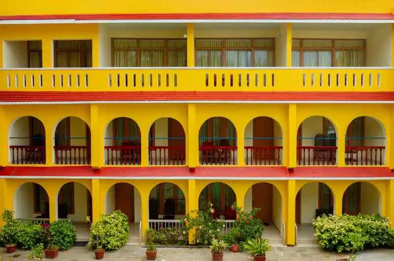 Yellow exterior facade with arched balconies at Jeevan Beach Resort Kovalam Kerala