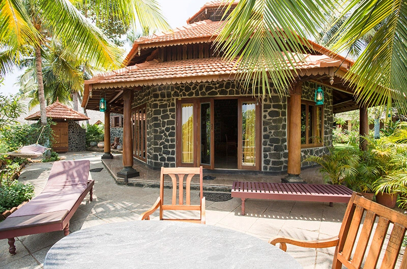 Kerala heritage wooden cottage with wooden sun loungers at Somatheeram Ayurvedic Health Resort
