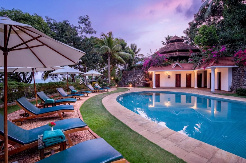 Outdoor swimming pool surrounded by tropical palm trees at Somatheeram Ayurvedic Health Resort Kovalam