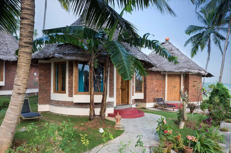 Scenic view of traditional wooden cottages surrounded by coconut palms at Somatheeram Ayurvedic Health Resort