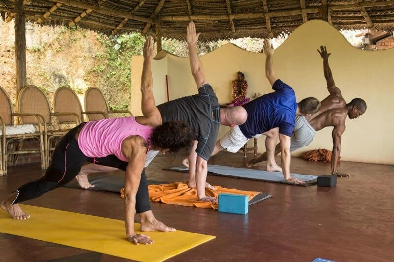 Guests practicing yoga on mats at open air pavilion in Somatheeram Ayurvedic Health Resort