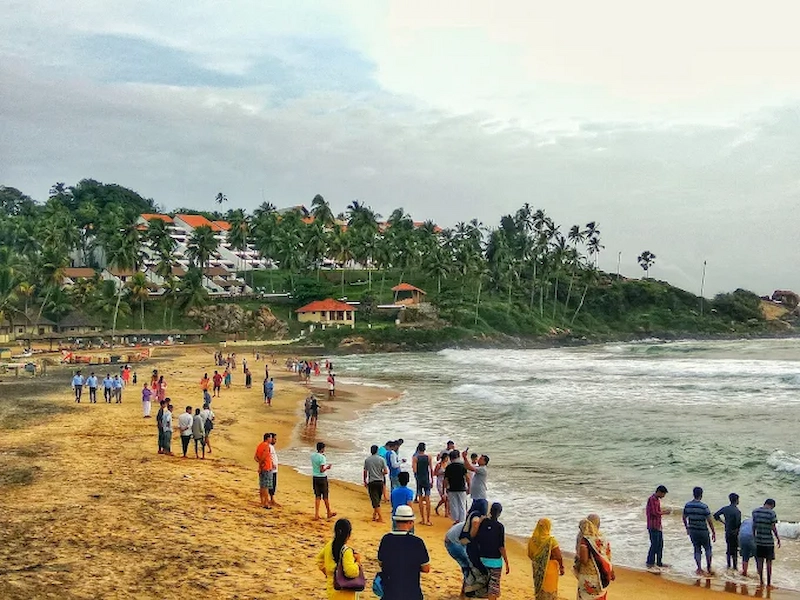 Crowded sandy beach at Kovalam in Kerala showing coastal erosion and ocean waves